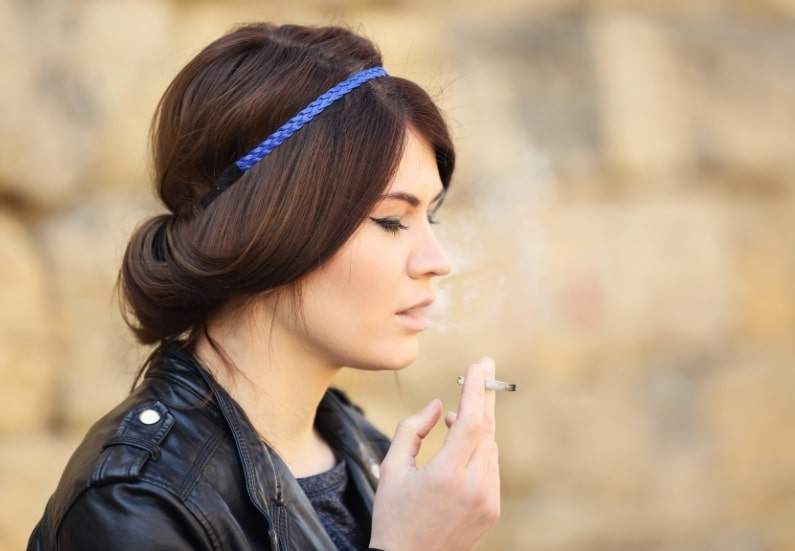 A person smoking cannabis outdoors, highlighting both the health risks and benefits associated with marijuana use.